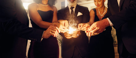 Fire, sparklers and people at a luxury party, event or celebration for new year with formal outfit. Celebrate, matches and group of friends in classy clothes at a black tie gala, banquet or dinner.の写真素材