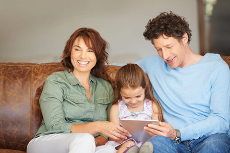 Raising the digital generation. a little girl and her parents using a digital tablet at home.