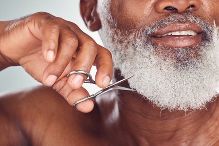 Black man face, beard with scissors and beauty with grooming and hygiene, shaving zoom isolated on studio background. Senior person skincare, dermatology and body hair removal, hand and clean nailsの写真素材