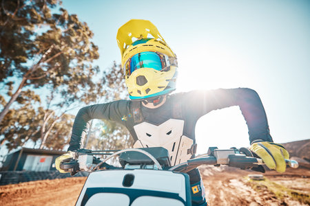 Motorcross, motorcycle and man in helmet for sports challenge, offroad race and desert sunshine. Driver, bike and gear for dirt track competition, motorbike performance and action on adventure course
