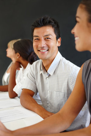 Ready for any challenge they throw at him. Young asian businessman sitting in a boardroom looking at camera.の写真素材
