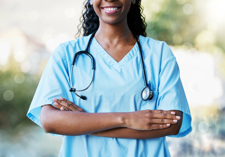 Healthcare, crossed arms and African female doctor with stethoscope standing in a garden in nature. Happy, smile and professional black woman medical worker in a medicare hospital after consultation.の写真素材