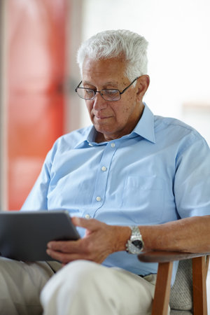 Keeping himself updated. a senior man using his digital tablet at home.