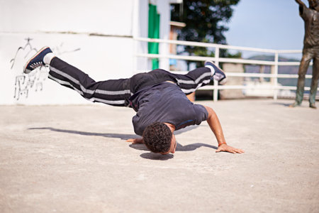 Dancing in the streets. Low angle shot of a young male breakdancer in an urban setting.の写真素材