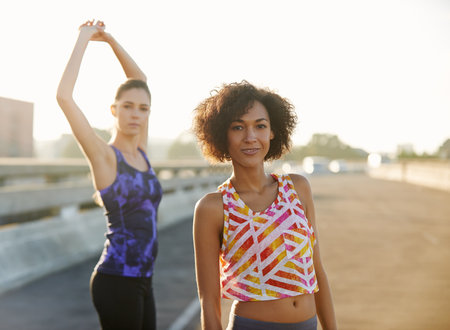Were ready for a long un. Portrait of two friends getting ready for a jog together through the city streets.の写真素材