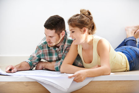Planning for the future. a young couple inspecting the building plans for their new home.の写真素材