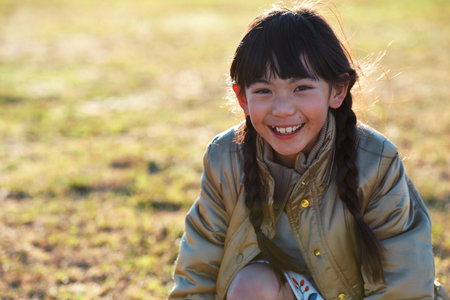 Portrait, Asian girl and playing in park, smile and carefree on holiday, summer and freedom. Young person, female child and kid with happiness, play game or on field for fun, relax and break on grassの写真素材