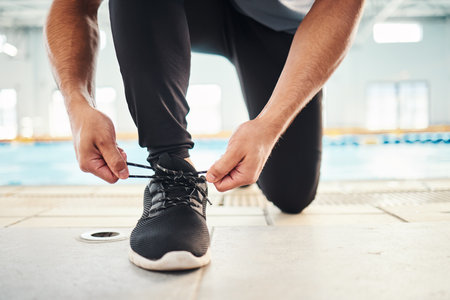 Lace shoes, swimming coach and man on ground for workout, training and wellness. Closeup guy tie sneakers for pool exercise, sports and water performance for healthy body, fitness goals and footwearの写真素材