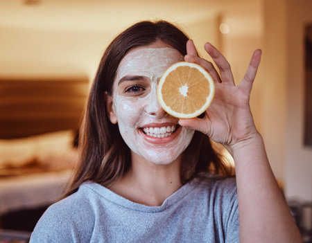 Skincare, orange and portrait of woman in her home for wellness, grooming and mask, treatment and facial. Fruit, face and girl relax with citrus product, natural and skin detox routine in her homeの写真素材