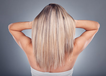 Back, hair care and woman with beauty, luxury and treatment for texture, volume and lady on grey studio background. Female, girl and hairstyle for confidence, salon grooming and shine on backdropの写真素材