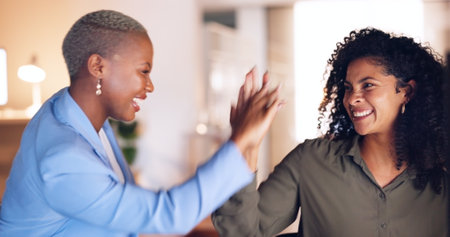 Collaboration, high five and business women in the office working together on a corporate project. Success, celebration and professional African employees in partnership planning a company strategy.の写真素材