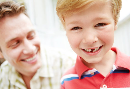 Growing up is full of changes. A young boy with a missing tooth spending time with his father.