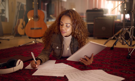 Musician, studio and woman writing lyrics for a song with paper and a digital tablet for composition. Creative, composer and female musical artist from Mexico working on a album, sound track or soundの写真素材