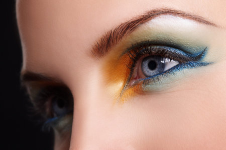 Bring that colour back into your face. Close up of a blue eye with yellow,green and blue eyeshadow.