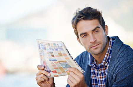 Thats something to think about. a man looking thoughtful while holding the newspaper.の写真素材