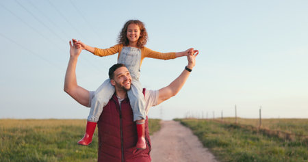 Happy family, father and child walking on a farm on a relaxed, calm and peaceful holiday vacation outdoors. Smile, happiness and young girl enjoys bonding and love having fun with dad in nature fieldの写真素材