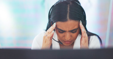 Stress, headache or woman in a call center with burnout exhausted by sales deadline pressure at help desk. Migraine pain, customer services or sick Indian telemarketing agent networking in officeの写真素材
