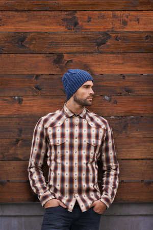 Street style. a handsome young man in trendy winter attire against a wooden background.の写真素材