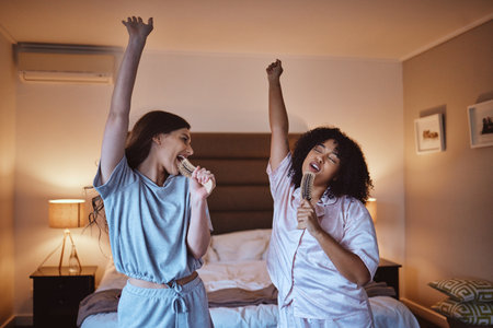 Friends, singing with brush and women in pajamas to get ready for girls night out dancing, fun music concert and happiness. Girl, friend and happy smile, girlfriends karaoke at sleepover in bedroom.の写真素材