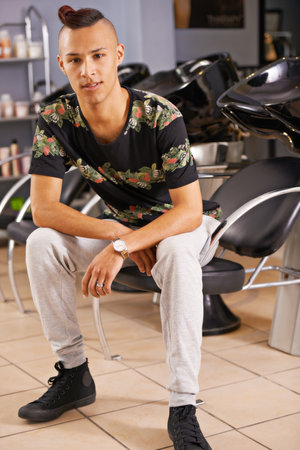 Choose your style. Portrait of a young male stylist sitting in a hair salon.の写真素材
