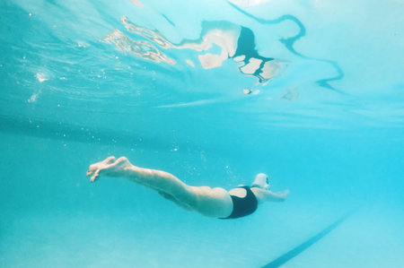 Swimming, fitness and sports with a woman underwater in a pool for cardio or endurance exercise. Water, swimwear and health with a female swimmer during a workout or competitive watersports gameの写真素材