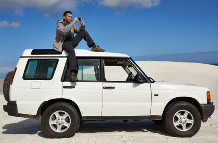 Getting a great shot. a group of a man sitting on a car and taking a photo.