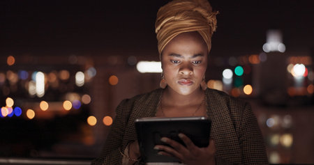 Tablet, night and balcony with a business black woman doing research while working outdoor at her...