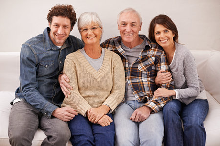 The in-laws arent so bad. A portrait of happy mature parents sitting with their adult children at...