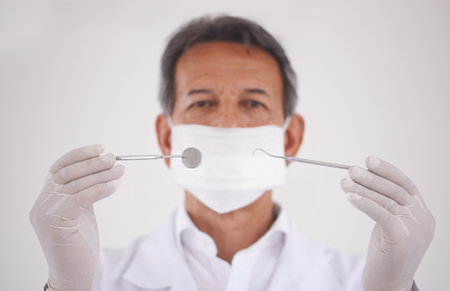 The tools of dentistry. Studio portrait of a dentist holding the tools of his trade.の写真素材