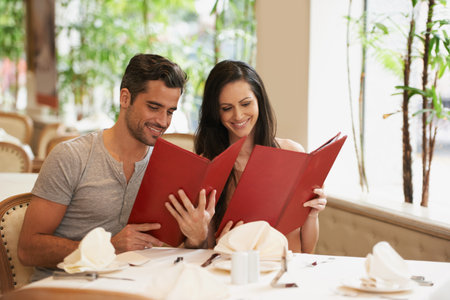 Lets order something special. A happy young couple on a date at a fancy restaurant.の写真素材
