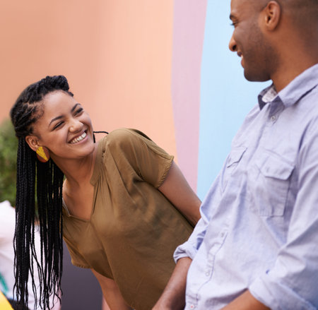 Sharing a loving laughing. a young couple laughing while leaning against a wall.