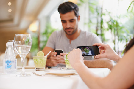 Capturing their times together. A woman taking a picture while dining out with her partner at a...