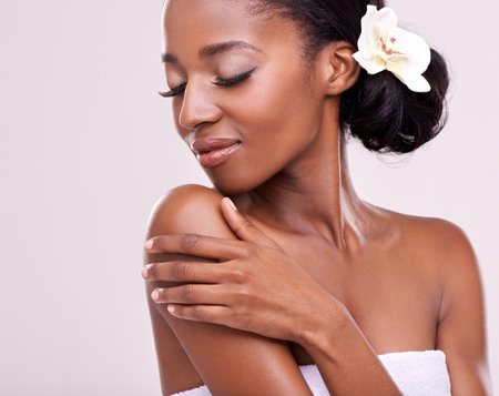 Silky soft and smooth. An isolated studio shot of a beautiful young woman touching her skin with her eyes closed.の写真素材