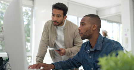 Businessman, startup and coaching conversation at desk with tablet, computer and question for mentor in office. Black man, web design coach and learning in workplace for support, advice or teamworkの写真素材