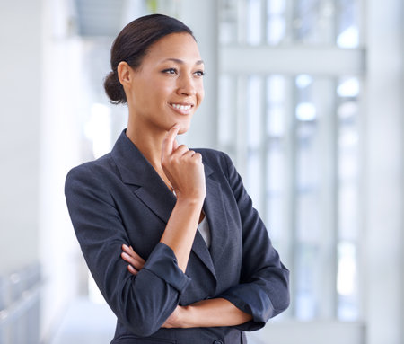 Thinking about her future. A young businesswoman looking away thoughtfully.の写真素材