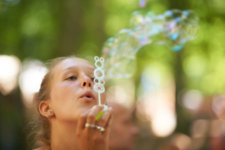 Everyone loves bubbles. a young woman blowing bubbles outside.