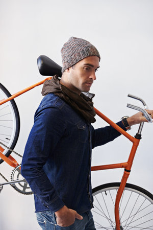 Time to cycle. a trendy young man carrying his bicycle.