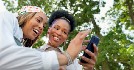 Friends with phone, funny meme on social media and relax outdoor during coffee break, communication and technology. Women together in city, comedy with 5g network and laughing at content onlineの写真素材