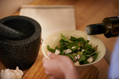 Healthy eating. a woman pouring oil over a bowl of salad.の写真素材