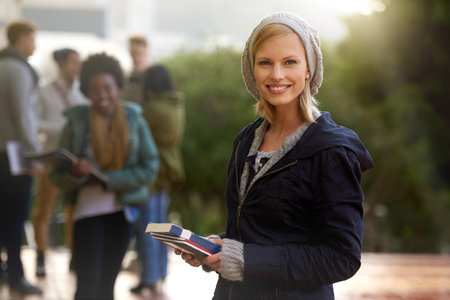 College life can be fun. Cropped portrait of a young woman standing on campus with other students in the background.の写真素材