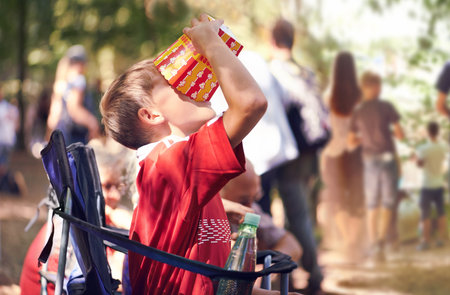 Enjoying some popcorn in the sun. a young boy eating popcorn outdoors.の写真素材