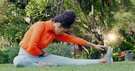 Black woman stretching leg in the park for fitness, health and wellness before a run. Exercise,...