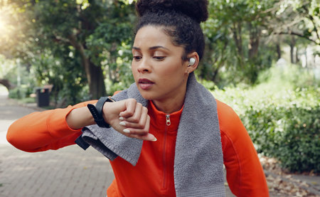Woman checking her pulse with a smart watch while on a health, fitness and wellness run in nature....
