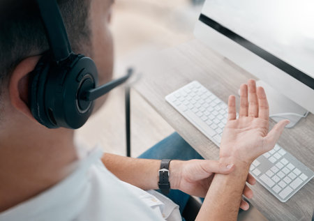 Pain, overworked and injured call center agent with hurt hand in the office suffering due to strain....