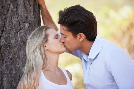 Lost in the romance. Closeup shot of a loving young couple kissing each other in the outdoors.の写真素材