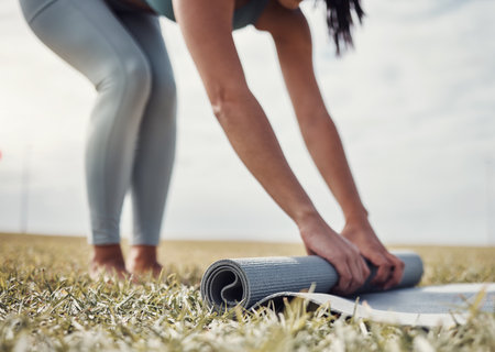 Roll, yoga or woman in nature to start body training, exercise or workout on grass for zen mindfulness. Hands, fitness or healthy person rolling a mat for a peaceful or calm meditation in summerの写真素材