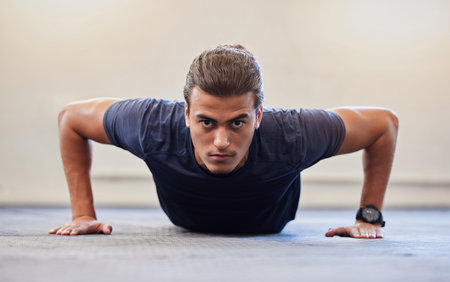 Fitness, portrait or push up with man in gym training or exercising in a body workout for endurance. Healthy male, strong or powerful sports athlete focused on floor exercise challenge for wellnessの写真素材