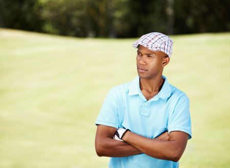 It was a long day on the course. a serious-looking african american golfer standing with his arms crossed.の写真素材