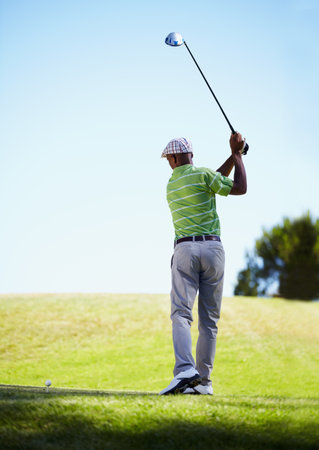 Perfect stroke. Rearview full length shot of a golfer in his follow through.の写真素材