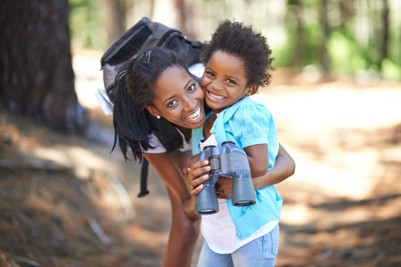 She loves a day outdoors. Portrait of a mother and daughter holding binoculars while out for a day in the forest.の写真素材